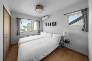 a white bedroom with a large bed and a window at The Vertex in Asahikawa