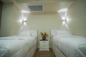 two beds in a room with white walls and lights at modern studio- 7 min from aswan station in Aswan