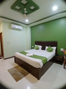 a bedroom with a bed with a green wall at Hotel Mahaveer Paradise Bilaspur in Bilāspur