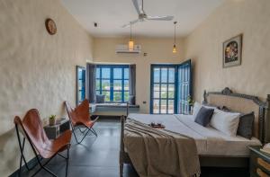 a bedroom with a bed and chairs and windows at SaffronStays Tarangini by Ganges in Rishīkesh