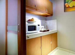 a kitchen with a microwave and a bowl of fruit at The Banyumas Villa in Denpasar