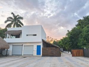 una casa bianca con una porta blu e una recinzione di Hotel Posada Mykonos a Bacalar