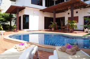 een zwembad met ligstoelen naast een huis bij The Oriental Tropical Beach at VIP Resort in Ban Phe