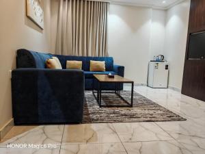 Una sala de estar con un sofá azul y una mesa. en شقق سويت ايلاف للشقق المخدومة اقتصادي, en Yeda