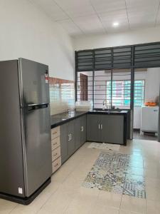 a large kitchen with a stainless steel refrigerator at CornerNest Bertam Homestay in Kepala Batas