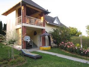 a house with a balcony and a chair in the yard at Rózsadomb Apartman in Zalakaros