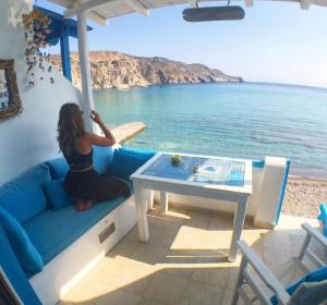 a woman sitting on a couch looking out at the ocean at Oneiro Beach Bungalow Studio in Plaka Milou