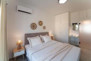 a white bedroom with a large bed with white walls at Gioiello Villa in Pefki Rhodes