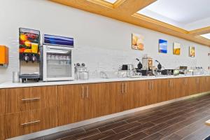 a large kitchen with wooden cabinets and a refrigerator at Comfort Suites Milledgeville in Milledgeville