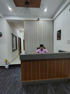 a man sitting at a counter in an office at NIKUNJ VAN By Hare Krishna Ambiance in Vrindāvan