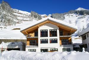 un edificio cubierto de nieve frente a una montaña en Alpina Appartements, en Schröcken