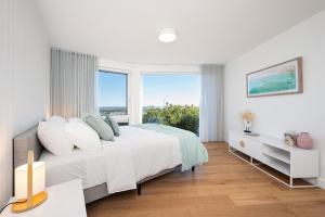 a white bedroom with a large bed and large windows at Horizons on Hove with Heated Spa in Rosebud