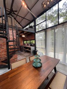 a dining room with a wooden table and some windows at Royal Brick Cottage, Jelebu in Kuala Kelawang