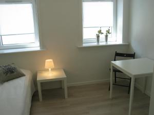 a room with a bed and a table and two windows at Aalborg City Rooms ApS in Aalborg