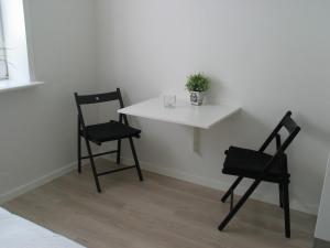 two chairs and a white table with a plant on it at Aalborg City Rooms ApS in Aalborg