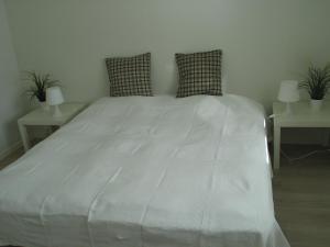 a large white bed with two tables and two pillows at Aalborg City Rooms ApS in Aalborg