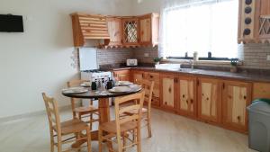 a kitchen with wooden cabinets and a table and chairs at Tal-Marga B&B in Qala