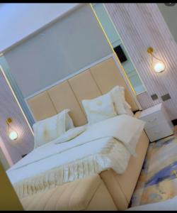 Un dormitorio con una cama grande con sábanas y almohadas blancas. en Ritz Luxury Apartments, en Kampala