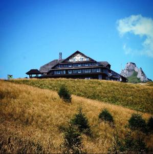 un edificio en una colina con una montaña en el fondo en Cabana Vârful Ciucaș, en Cheia