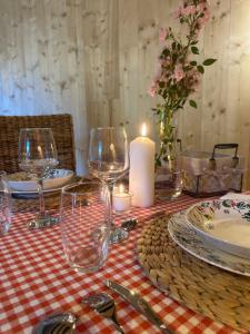 a table with glasses and plates and a candle at Les Chambres du 11 - Chambres et Table d'hôtes in Chevigny