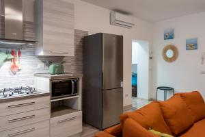a kitchen with a stainless steel refrigerator next to a couch at Al Laghée - New 2 Bedroom Apartment in Gravedona Center in Gravedona