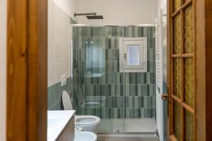 a bathroom with a toilet and a green tiled wall at Al Laghée - New 2 Bedroom Apartment in Gravedona Center in Gravedona +38 photos
