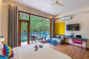 a living room with a large window and a couch at goSTOPS Kasol PLUS, Manikaran Road - Private Rooms & Dorms in Kasol