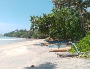 three boats sitting on a beach next to the ocean at Albergo Marina Nilwella in Dickwella