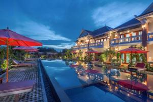 a resort pool with red umbrellas and chairs at Amour D' Angkor in Phumĭ Réach Born (1)
