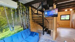 a living room with a blue couch and a spiral staircase at Wiśniowe Zacisze - Agroturystyka in Sułkowice