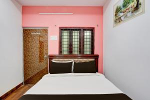 Un dormitorio con una cama y una pared rosa. en Hotel O Heavens Inn, en Hyderabad