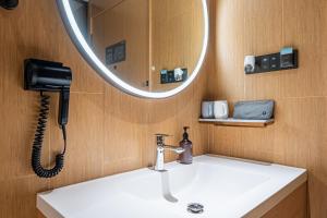 a bathroom with a sink with a phone and a mirror at JI Hotel Beijing West Railway Station in Beijing +1 photo