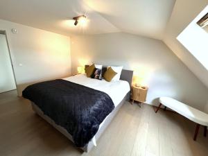 a bedroom with a large bed with a black blanket at ZEEZANDPAREL Westende-Bad Gezellig 3-slaapkamer appartement in Westende-Bad