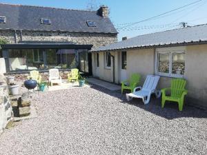 eine Terrasse mit grünen Stühlen und ein Haus in der Unterkunft Le Cottage " Village de La Ruée " Location de vacances in Plurien