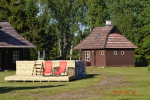 zwei rote Stühle auf einer Terrasse vor einem Haus in der Unterkunft Kase Holiday Center in Paiküla