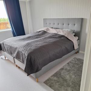 a bedroom with a bed with a gray blanket and a window at Helt ny sentral 2-roms leilighet i Dyrøy in Brostadbotn
