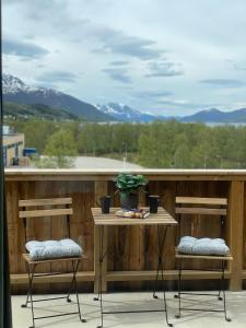 a balcony with two chairs and a table with a plant at Helt ny sentral 2-roms leilighet i Dyrøy in Brostadbotn +29 photos