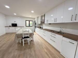 eine Küche mit weißen Schränken und einem Tisch mit Stühlen in der Unterkunft Casa Aldea de Piñeiro, Turismo Rural Padrón by URent in Padrón + 12 Fotos