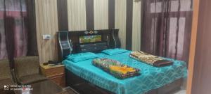 a bedroom with a bed with blue sheets and a chair at Hotel Gauri & Restaurant in Jāmb