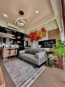 a living room with a couch and a chandelier at Asha suite by Patraland Amarta Apartemen in Kejayan