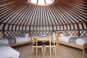 Cette yourte comprend 2 lits et une table. dans l'établissement Premium Bolor Resort, Terelj, à Nalayh