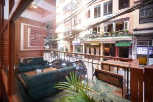 a balcony with a couch and tables on a city street at Hotel Cozy Heaven in Kathmandu