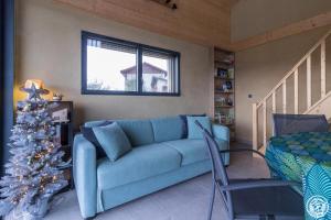 a living room with a blue couch and a christmas tree at La joline, maison bioclimatique in Montastruc-de-Salies