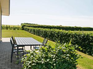 a wooden table and chairs on a patio with bushes at 5 star holiday home in Sydals in Mommark