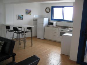 una cocina con mesa y sillas y una cocina con electrodomésticos blancos. en Mirador del Roque, en Orzola
