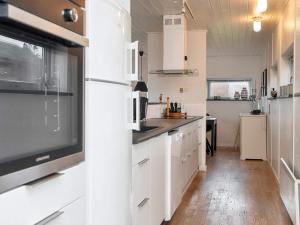 a kitchen with white cabinets and a flat screen tv at 8 person holiday home in Knebel-By Traum in Knebel