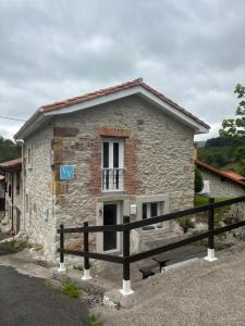 a stone house with a window and a fence at Vivienda Vacacional La Yaya in Ortiguero