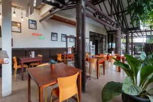 a restaurant with wooden tables and chairs and plants at Jayagiri Guesthouse By Belgareti in Lembang