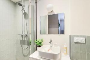 Un baño blanco con lavabo y ducha. en Studio cosy et pratique, proche métro, par de la tête d'or, en Lyon