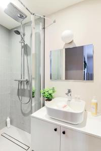 Un baño blanco con lavabo y ducha. en Studio cosy et pratique, proche métro, par de la tête d'or, en Lyon
